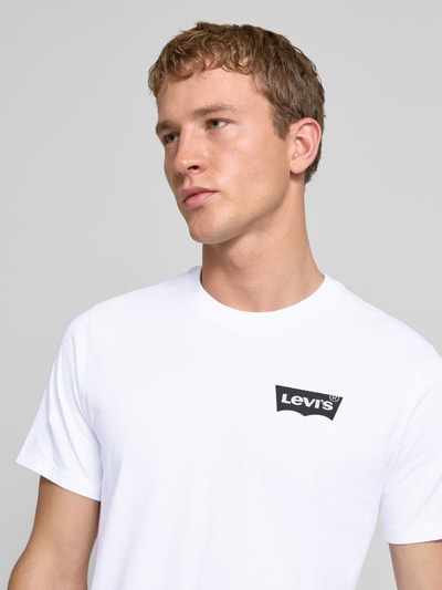 Männermodel trägt T-Shirt mit Label-Print von Levi's®, weiß, reine Baumwolle, Regular Fit, gerippter Rundhalsausschnitt, Nahaufnahme Oberkörper.