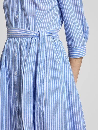 Frauenmodel trägt Hemdblusenkleid mit Bindegürtel und 3/4-Arm von Oui aus Reine Baumwolle, hellblaue und weiße Streifen, Detailaufnahme. A-Linie, Midikleid, Hemdblusenkragen, Knopfleiste, Rückenlänge bei Größe 36: 120 cm, Brustweite: 48 cm, Ärmellänge: 46 cm.