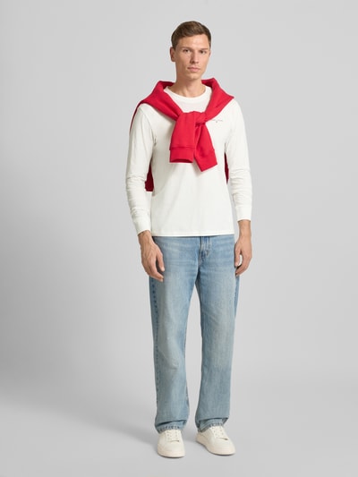 Männermodel trägt Slim Fit Langarmshirt aus reine Baumwolle von Tommy Jeans, Optik: Unifarben, Ganzkörperansicht von vorne.