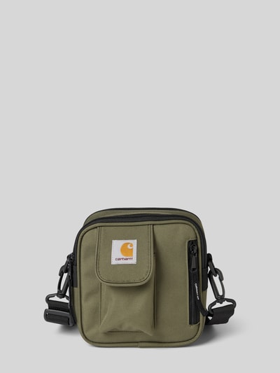 Produktfoto, Essentials Bag mit Logo-Patch von Carhartt Work In Progress, olivgrün, rechteckig, mit Reißverschluss und abnehmbarem Schulterriemen, Hauptfach und Reißverschlussfach innen, Maße 18x18x8 cm, Schulterriemen 78 cm.