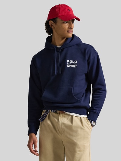 Männermodel trägt Relaxed Fit Hoodie aus Baumwoll-Mix von Polo Ralph Lauren in uni dunkelblau mit Label Print, kangoeroezak, ribboord, sweat textuur, voorkant, nahaufnahme oberkörper