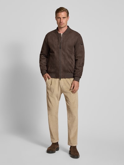 Männermodel trägt Straight Fit Hose aus Baumwoll-Mix Modell 'Chasy' von DRYKORN in Cord-Optik, beige Farbe, Ganzkörperansicht von vorne. Elastischer Bund, Gesäßtaschen, Bundweite 40 cm, Innenbeinlänge 71 cm, Knopf- und Reißverschluss.