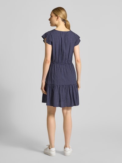 Vrouwenmodel draagt 'Minikleid aus reiner Viskose mit V-Ausschnitt' van GAP, donkerblauw met witte stippen, getailleerde pasvorm, tunnelkoord in taille, mini-jurk met korte mouwen van zuiver viscose, borstwijdte maat S 85 cm, mouwlengte 11 cm, volledig beeld van achteren.