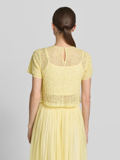 Frauenmodel trägt Cropped T-Shirt mit Pailletten von LACE & BEADS, Damen T-Shirt aus Mesh in Gelb, Rundhalsausschnitt, Rückenlänge 41 cm bei Größe S, Ganzkörperansicht Rückansicht.