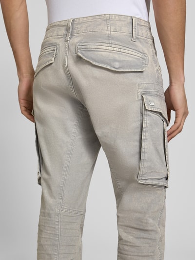 Männermodel trägt Regular Tapered Fit Hose mit Cargotaschen Modell 'Rovic' von G-Star Raw, bawełna z elastanem, używany wygląd, szare odcienie, szerokość w rozmiarze 32/32: 44 cm, długość nogawki 78 cm, zdjęcie całych pleców.