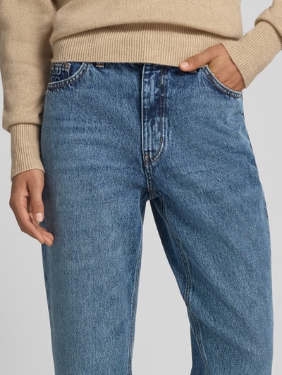 Frauenmodel trägt Mom Fit Jeans aus reiner Baumwolle im 5-Pocket-Design von HUGO, mittleres Blau, sichtbare Denim-Textur, Nahaufnahme Oberkörper, Damen Mom Fit Jeans von HUGO.