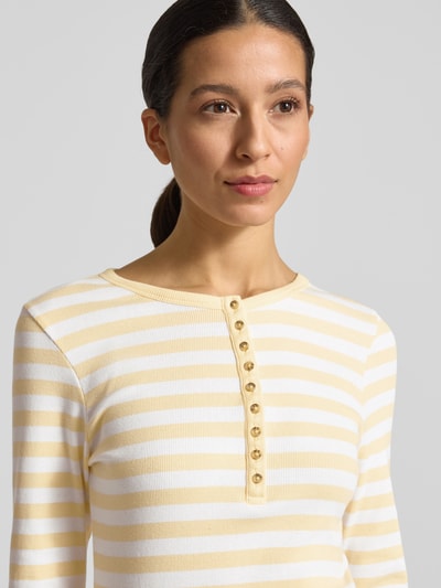 Frauenmodel trägt Longsleeve mit kurzer Knopfleiste von Christian Berg Woman im gelb-weiß gestreiften Bio-Baumwoll-Mix, Slim Fit, Nahaufnahme Oberkörper.