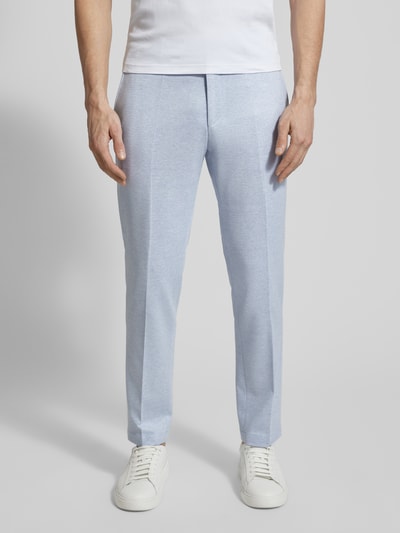 Männermodel trägt hellblaue Hose mit Bügelfalte, kombiniert mit weißem Shirt und Sneakers, glatte Textur, Nahaufnahme Beine.