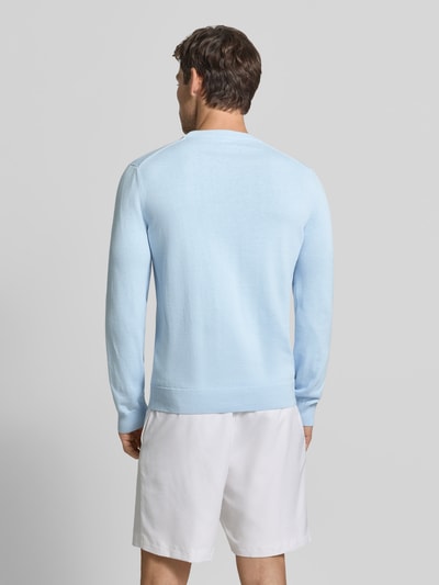Männermodel trägt hellblauen Regular Fit Pullover aus Baumwoll-Mix von Lacoste, weiße Shorts, Ganzkörperansicht Rückansicht. Herren Pullover von Lacoste