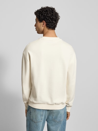 Männermodel draagt Regular Fit Sweatshirt aus reiner Baumwolle Modell 'NIEROFIX_CREW' van Hugo Blue in uni crème, rugaanzicht, lange mouwen, geribbelde boorden.
