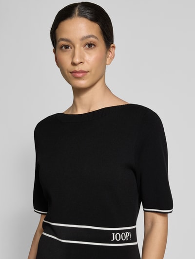 Frauenmodel trägt Regular Fit Kleid aus Viskose-Mix Modell 'Kirla' von JOOP! in Schwarz mit Strick-Optik, Halbarm, Logo-Stitching, Nahaufnahme Oberkörper.