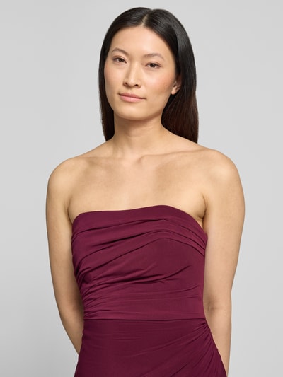 Frauenmodel trägt Slim Fit Abendkleid in Maxilänge mit Gehschlitz von Hey Kyla im Elastischer-Material-Mix, Schulterfrei, Raffung, Nahaufnahme Oberkörper. Rückenlänge bei Größe 36: 132 cm, Brustweite: 28 cm. Farbe: dunkles Bordeaux.