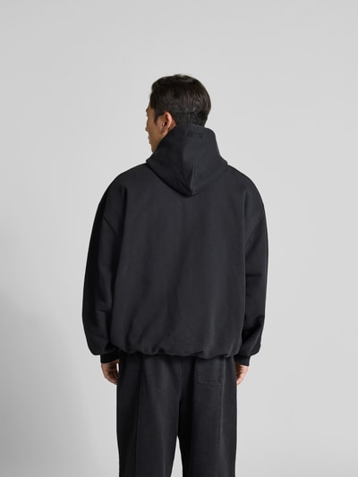 Männermodel trägt Oversized Sweatjacke mit Foto-Print von VETEMENTS aus Baumwoll-Mix, oversized, Kapuze mit Tunnelzug, Rückenlänge 74 cm, Schulterbreite 68 cm, Ärmellänge 67 cm, Zweiwege-Reißverschluss, schwarze Farbe, glatte Textur, Ganzkörperansicht Rückansicht.