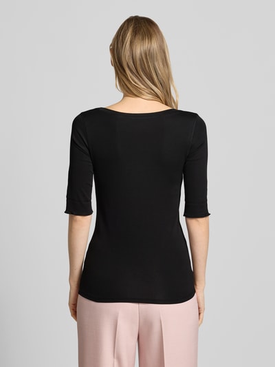 Modelka nosi t-shirt z zakładką na rękawach i okrągłym dekoltem od Marc Cain, mieszanka bawełny z dodatkiem streczu, dopasowany krój, detal z logo, długość tyłu w rozmiarze 36: 60 cm, widok całej sylwetki z tyłu