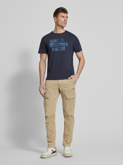 Männermodel trägt Cargohose mit Label-Stitching von PME Legend, Beige, Material-Mix mit Stretch-Anteil, Slim Fit, Cargotaschen, Ganzkörperansicht von vorne.