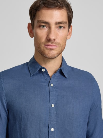 Männermodel trägt Regular Fit Leinenhemd aus reinem Leinen Modell 'CORE' von Scotch & Soda in Blau mit durchgehender Knopfleiste, Kentkragen, Langärmelig, Label-Stitching, Nahaufnahme Oberkörper. Rückenlänge bei Größe M: 78 cm, Schulterbreite 45 cm, Ärmellänge 66 cm.