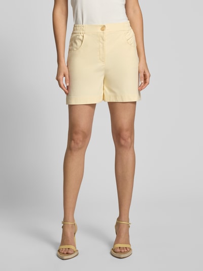 Frauenmodel trägt Shorts mit elastischem Bund Modell 'KATE' von ICHI aus Baumwoll-Mix mit Stretch-Anteil, Regular-Fit, Eingrifftaschen, helles Gelb, glatte Struktur, Ganzkörperansicht von vorne.