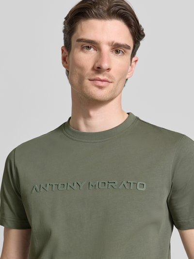 Męski model nosi T-Shirt mit Label-Print od Antony Morato, czysta bawełna, krój regular fit, okrągły dekolt, nadruk z logo, długość tyłu w rozmiarze M: 72 cm, zbliżenie górnej części ciała z przodu.