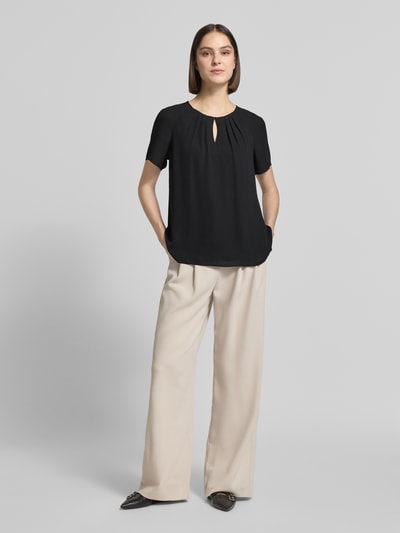 Frauenmodel trägt Blusenshirt mit Schmetterlingsärmeln und Schlüsselloch-Ausschnitt von Comma, schwarze Loose-Fit-Bluse mit Raffungen, Ganzkörperansicht von vorne. Rückenlänge 66 cm, Ärmellänge 16 cm bei Größe 36.
