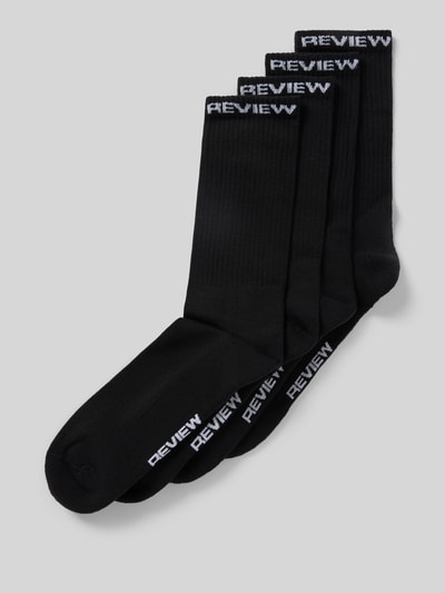 Produktfoto, Socken aus Baumwoll-Mix im 4er-Pack von REVIEW, schwarz mit weißem Logo-Detail am elastischen Bund, glatte Textur.