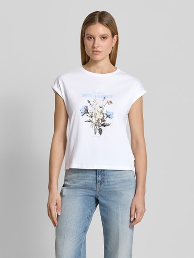 Frauenmodel trägt Relaxed Fit T-Shirt aus reiner Baumwolle von s.Oliver RED LABEL, Optik: Unifarben, Front-Print, Label Print, überschnittene Schultern, Rundhals, Ärmelform: kurzarm, Ärmelabschluss mit Umschlag, Material: reine Baumwolle, sanfte Weiß- und Blautöne, glatte Textur, Ganzkörperansicht von vorne.
