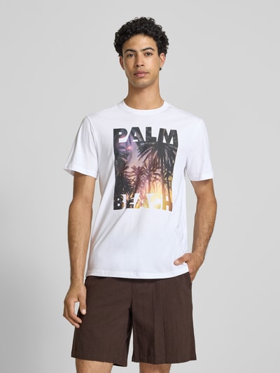Männermodel trägt Regular Fit T-Shirt aus reiner Baumwolle Modell 'MAGDY LIFE' von Only & Sons, weiß mit Foto-Print, Ganzkörperansicht von vorne.