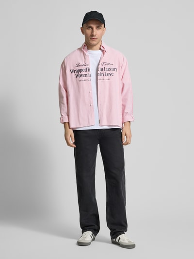 Männermodel trägt Regular Fit Freizeithemd mit Button-Down-Kragen von ANOTHER COTTON LAB aus Baumwoll-Mix in Rosa mit Label-Print, Ganzkörperansicht von vorne.
