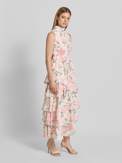 Vrouwenmodel draagt vrijetijdsjurk met meerkleurige look, getailleerd, midilengte, hooggesloten hals, bloemenmotief, volants, materiaalverwerking chiffon, model 'FELICIA' van Vero Moda, detailopname, schuin van voren.