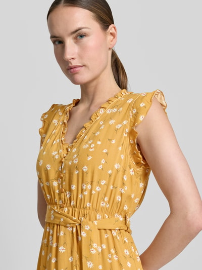 Frauenmodel trägt Minikleid aus Viskose mit Bindegürtel und Kappärmeln von Apricot, senfgelb, Blumenmuster, Taillierter Schnitt, Nahaufnahme Oberkörper.