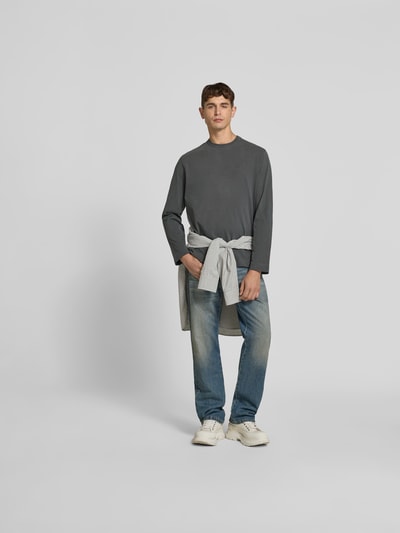Männermodel trägt Relaxed Fit Longsleeve aus Baumwolle von Forét in Grau mit Used-Look, Label-Stitching, Ganzkörperansicht von vorne. Herren Longsleeve aus Reine Baumwolle, Rundhalsausschnitt, Rückenlänge 71 cm bei Größe M.