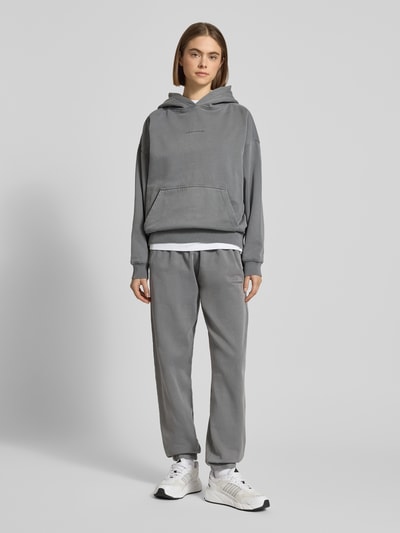 Modelka nosi High Waist Sweatpants mit elastischem Bund od Pegador, szare, z bawełnianego miksu, logo, kieszenie, widok całościowy z przodu.