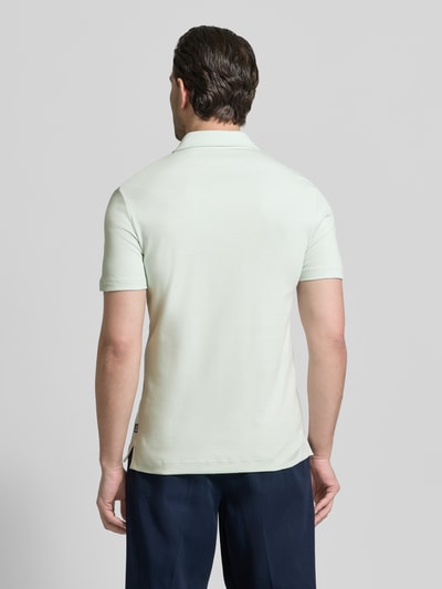 Männermodel trägt Slim Fit Poloshirt aus reiner Baumwolle Modell 'PALOSH 30' von BOSS in Unifarbe, Ganzkörperansicht Rückansicht.