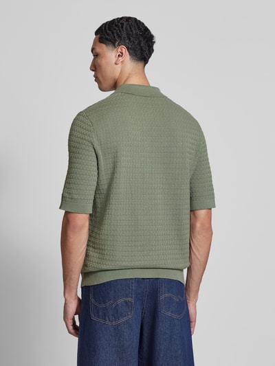 Männermodel trägt Regular Fit Poloshirt aus reiner Baumwolle Modell 'MENU' von Only & Sons in Olivgrün mit Flechtoptik, Ganzkörperansicht Rückansicht.