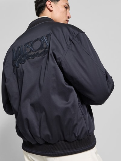 Männermodel trägt Blouson mit Stehkragen von MAISON KITSUNÉ in Dunkelblau, lockere Passform, Rückansicht, Detailaufnahme Oberkörper.