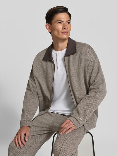 Männermodel trägt Jacke aus Baumwoll-Mix Modell 'Arelio' von DRYKORN, beige kariert, lockere Passform, Nahaufnahme Oberkörper.