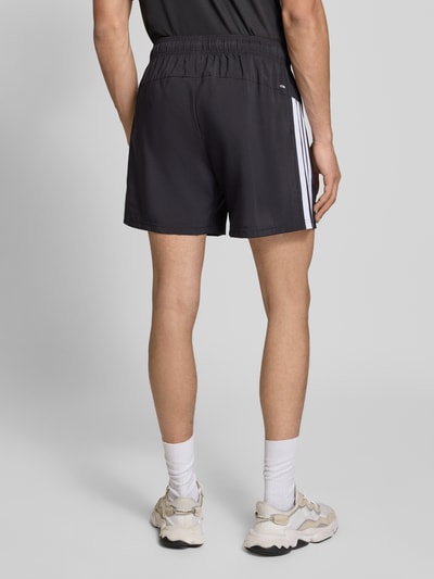 Männermodel trägt schwarze Shorts mit Logo-Print und Reißverschlusstaschen von adidas Training, Lockerer-Schnitt, Ganzkörperansicht Rückansicht.