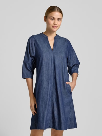 Frauenmodel trägt knielanges Jeanskleid mit V-Ausschnitt Modell 'Wonema' von OPUS in A-Linie aus reiner Baumwolle, Ganzkörperansicht von vorne.