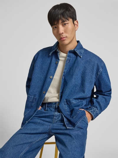 Männermodel trägt Freizeithemd in Denim-Optik von WON HUNDRED aus reiner Baumwolle, Relaxed-Fit, aufgesetzte Taschen, durchgehende Knopfleiste, Ganzkörperansicht von vorne.