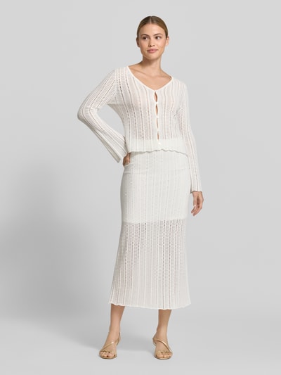 Frauenmodel trägt Cardigan mit V-Ausschnitt und Knopfleiste von Rich & Royal aus Reine Baumwolle, Straight Fit, Ajour-Strick, weiße Farbe, Trompetenärmel, Rückenlänge 52 cm, Ärmellänge 62 cm, Ganzkörperansicht von vorne.