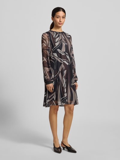 Frauenmodel trägt Knielanges Kleid mit Rundhalsausschnitt von Betty Barclay im Material-Mix mit Stretch-Anteil, taillierter Schnitt, abstraktes Muster in Braun- und Beigetönen, knielang und blickdichtes Unterkleid, Ganzkörperansicht von vorne.