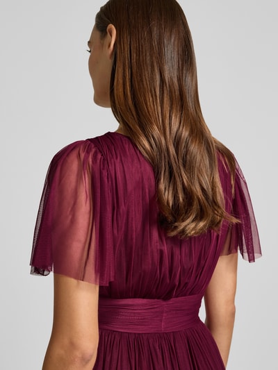 Vrouwenmodel draagt 'Abendkleid met diepe V-hals' van LACE & BEADS in bordeauxrood, laagjeslook, A-lijn, tailleband, ruglengte maat S 149 cm, borstwijdte maat S 38 cm, mouwlengte maat S 27 cm, detailopname bovenlichaam rugaanzicht.