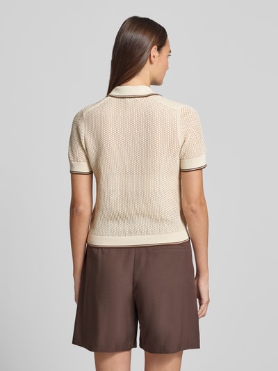Vrouwenmodel draagt gebreid shirt met polokraag en knoopsluiting model 'MEROPE' van DRYKORN, puur katoen, regular fit, ruglengte 50 cm, mouwlengte 20 cm. Ganzkörperansicht Rückansicht.