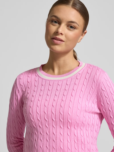 Kobiece model prezentuje Strickpullover mit gerippten Abschlüssen od Christian Berg Woman, bawełniany mix, krój regular fit, okrągły dekolt, różowy z fakturą warkoczową, detal żebrowany, długość tyłu w rozmiarze S: 60 cm, długość rękawa w rozmiarze S: 64 cm, zbliżenie na górną część ciała.