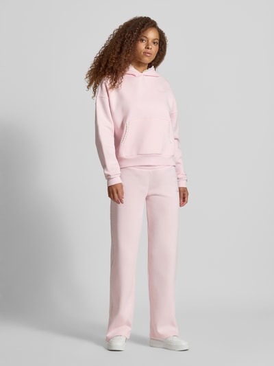 Frauenmodel trägt Hoodie mit Häkelspitzenbesatz von REVIEW in zartem Rosa, Baumwollmischung, lockere Passform, Ganzkörperansicht von vorne.
