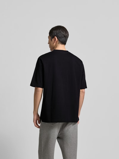 Männermodel trägt Loose Fit T-Shirt aus reiner Baumwolle von Dsquared2 in Schwarz mit verlängerter Rückseite, Ganzkörperansicht Rückansicht.