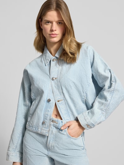 Frauenmodel trägt Jeansjacke mit Eingrifftaschen Modell 'DOLEMAN TRUCKER' von Calvin Klein Jeans in heller Jeans-Optik, Reine Baumwolle, Gerader-Schnitt, Kentkragen, Knopfleiste, Nahaufnahme Oberkörper.