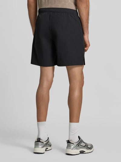 Mężczyzna nosi Relaxed Fit Sportshorts mit elastischem Bund od BOSS Green, czarne, gładkie, widok całej sylwetki z tyłu.