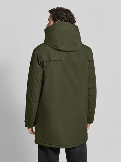 Männermodel trägt Parka mit Kapuze und Pattentaschen Modell 'AIDEN' von Didriksons in Olivgrün, Rückenansicht, Ganzkörperansicht Rückansicht. Regular Fit, verdeckter Reißverschluss, strukturierte Oberfläche, Kontext: Rückenlänge 95 cm, Schulterbreite 47 cm, Brustweite 55 cm, Ärmellänge 68 cm.