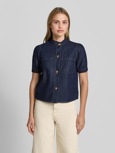 Modelka kobieta nosi Regular Fit Jeansbluse mit Brusttaschen od More & More z czystej bawełny, stójka, krótkie rękawy, niebieski denim, guziki, kieszenie na piersi, długość tyłu 52 cm w rozmiarze 36, długość rękawa 25 cm w rozmiarze 36, widok całej sylwetki z przodu