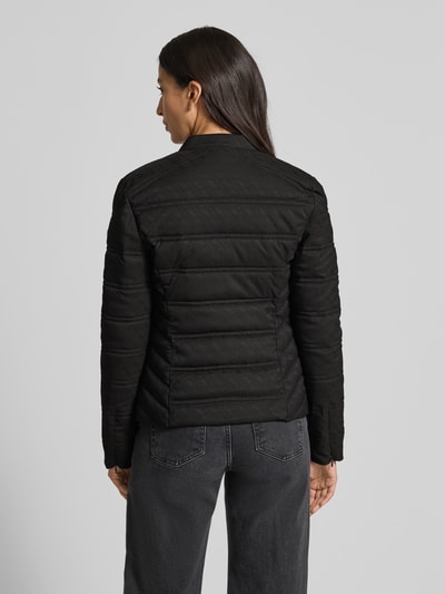 Kobiece modelka nosi czarną kurtkę pikowaną z mieszanki materiałów z dodatkiem streczu, wzór z logo, stójka, zamek błyskawiczny, kieszenie na zamek, krój slim fit, model 'NEW VONA' od Guess, widok całej sylwetki z tyłu.
